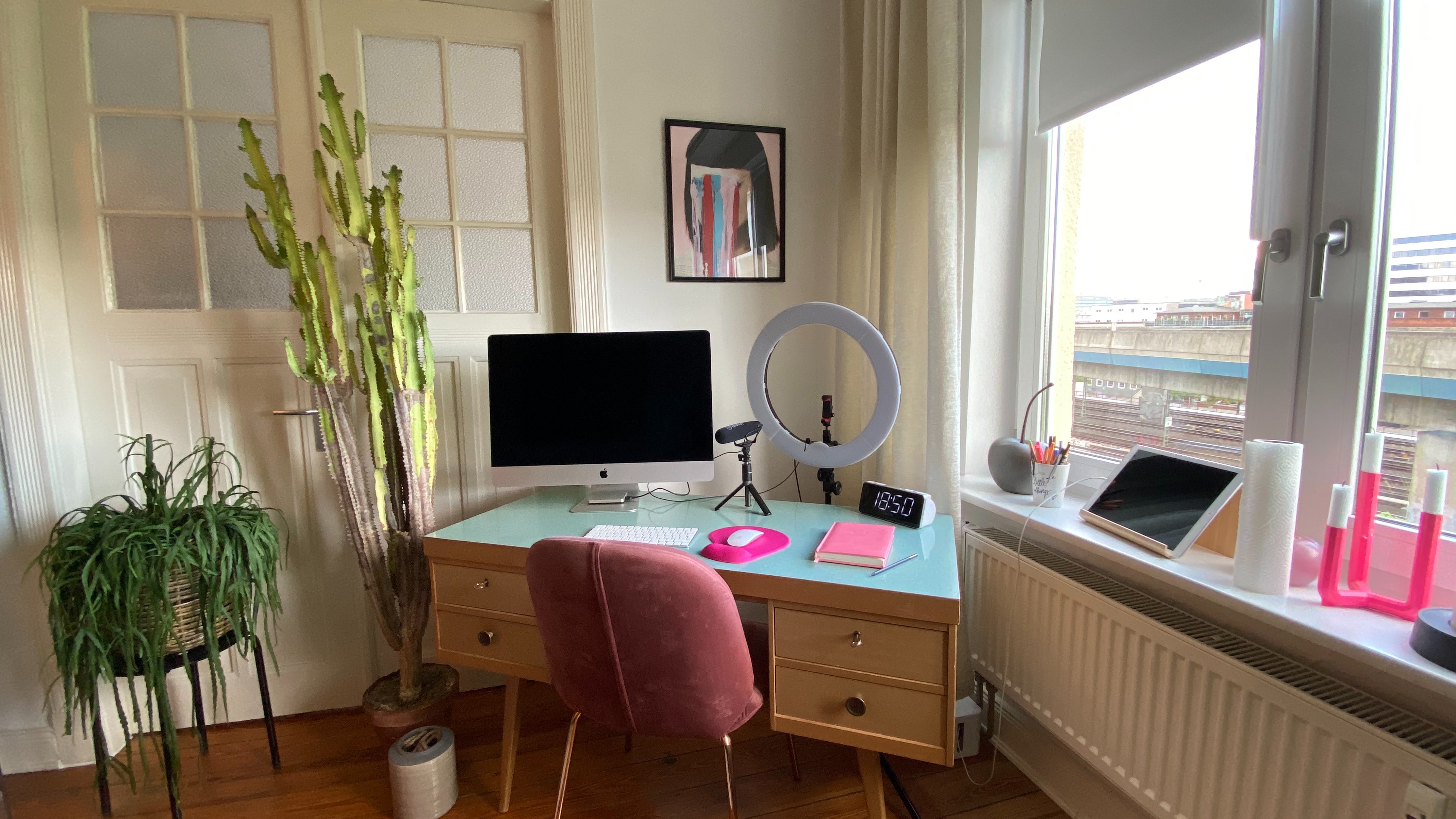 black flat screen computer, a led tripod and a pink notebook on top of a wooden table