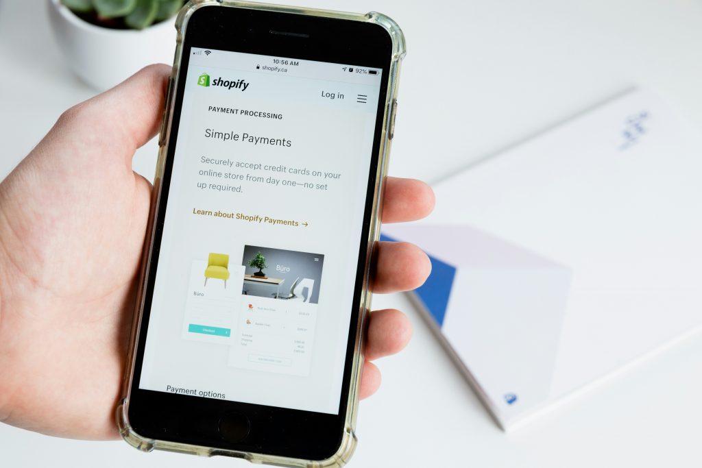 Dropshipping as a Side Hustle in 2025: What Still Works and What’s Dead - Josei Life - man holding a smartphone showing shopify simple payments